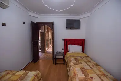a room with two beds and a tv on the ceiling at Riad Assia in Marrakech