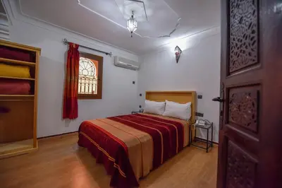 a bedroom with a bed with a red blanket and a window at Riad Assia in Marrakech