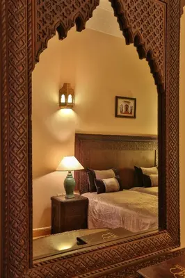 a mirror in a room with a bed and a lamp at Riad & Spa Bahia Salam in Marrakech
