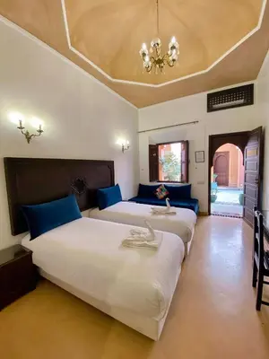 a bedroom with two beds and a chandelier at Riad & Spa Bahia Salam in Marrakech