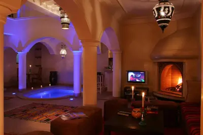 a living room with a swimming pool and a fireplace at Riad L'Emir in Marrakech