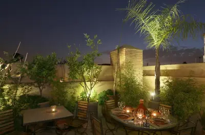 a patio with a table and chairs at night at Riad L'Emir in Marrakech