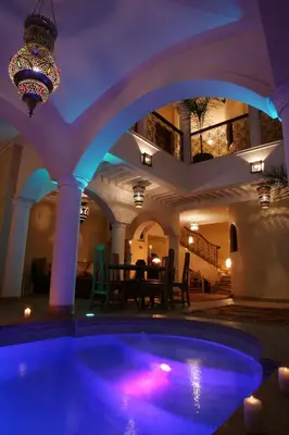 a swimming pool in a building with a purple lighting at Riad L'Emir in Marrakech