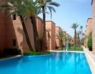 a large blue swimming pool with palm trees next to a building at Ryad Nayla in Marrakech