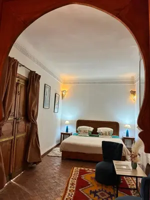 a bedroom with a bed and a chair in a room at Riad Chameau FDC Hôtel SPA in Marrakech