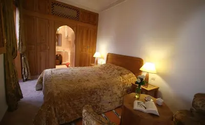a bedroom with a bed and a table with a book at Riad Chameau FDC Hôtel SPA in Marrakech