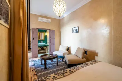 a room with a bed and a chair and a table at Riad Beldi in Marrakech
