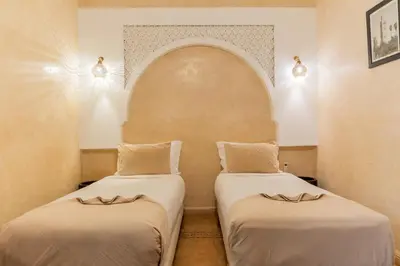 two beds in a room with an arched niche at Riad Beldi in Marrakech