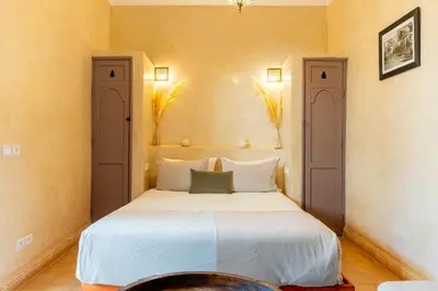 a bedroom with a white bed and two doors at Riad Beldi in Marrakech