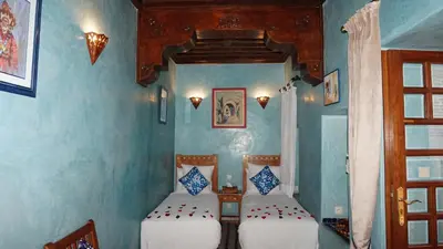 two beds in a room with blue walls at Riad Samsli in Marrakech