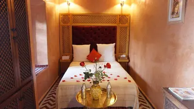 a bedroom with a bed with a vase of flowers on a table at Riad Samsli in Marrakech