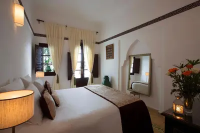 a bedroom with a large white bed and a mirror at Riad Dar Alfarah in Marrakech