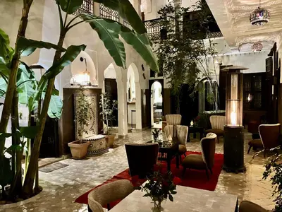 a lobby with tables and chairs and plants at Riad Aya in Marrakech
