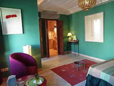 a bedroom with green walls and a bed and a table at Dar Taliwint in Marrakech