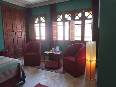 a room with two chairs and a table and windows at Dar Taliwint in Marrakech
