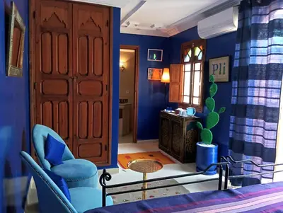 a blue room with a door and a table and chairs at Dar Taliwint in Marrakech