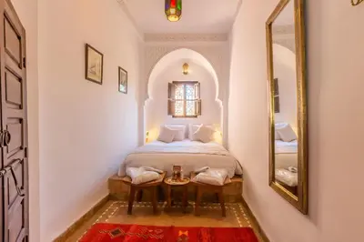 a small bedroom with a bed and a mirror at Riad Amin in Marrakech