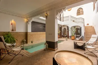 a pool in a room with chairs and a table at Riad Amin in Marrakech