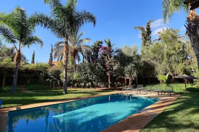 a swimming pool in a yard with palm trees at Villa de Luxe Domaine des Kasbahs in Marrakech