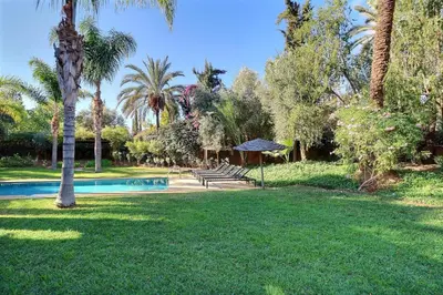 a yard with a swimming pool and palm trees at Villa de Luxe Domaine des Kasbahs in Marrakech