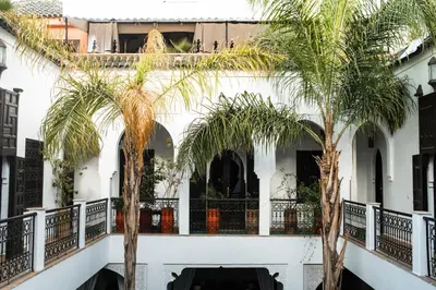 a white building with palm trees in front of it at Riad Pachavana in Marrakech