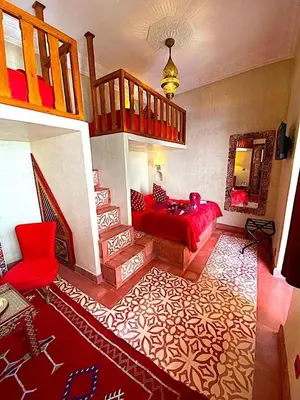 a living room with a red couch and a staircase at Riad La Perle Rouge in Marrakech