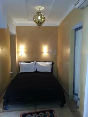 a bedroom with a bed with two pillows and a chandelier at Riad AZZA in Marrakech