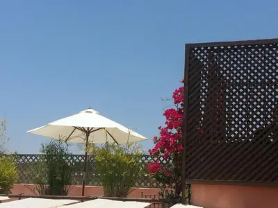 a white umbrella and some flowers on a fence at Riad AZZA in Marrakech
