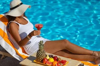 a woman sitting in a chair with a drink and a tray of fruit at Pickalbatros Hôtel Du Golf - Adults Friendly 16 Years Plus- All-Inclusive in Marrakech