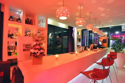a bar in a restaurant with red chairs and lights at Cesar Resort & Spa in Marrakech