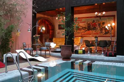 a large swimming pool with chairs and a table at Riad Malika in Marrakech