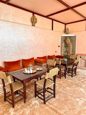 a dining room with tables and chairs and a couch at Riad Tasneem in Marrakech