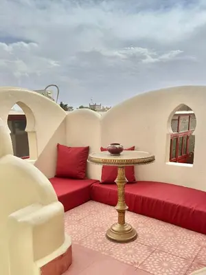 a balcony with red cushions and a table with a bowl on it at Riad Tasneem in Marrakech