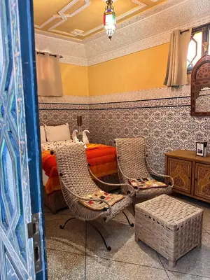 a bedroom with a bed and two wicker chairs at Riad Tasneem in Marrakech