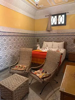a bedroom with a bed and two wicker chairs at Riad Tasneem in Marrakech