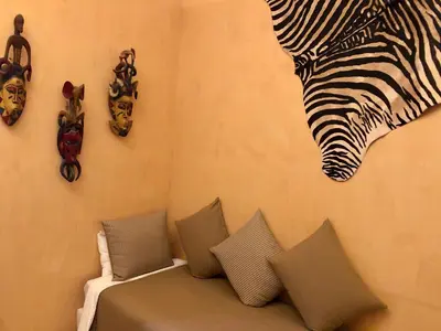 a wall with a couch with pillows and a zebra painting at Riad Bellamane Marrakech in Marrakech