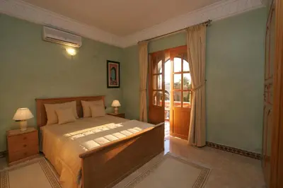 a bedroom with a bed and a door to a balcony at Villa Zahra Palmeraie in Marrakech