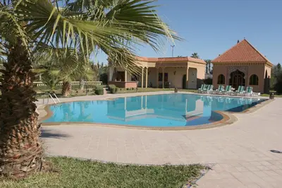 a swimming pool in front of a house with a palm tree at Villa Zahra Palmeraie in Marrakech
