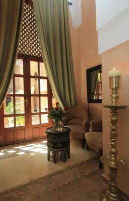 a living room with green curtains and a table with flowers at La Villa Nomade in Marrakech