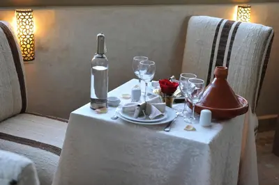 a table with a bottle of wine and glasses on it at Riad Anjar in Marrakech