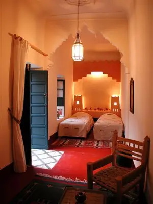 a bedroom with two beds and a room with two chairs at Riad El Filali in Marrakech