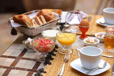 a table with a breakfast of eggs bread and juice at Riad Zayane in Marrakech