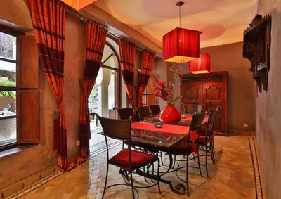 a dining room with a red table and chairs at Riad Zayane in Marrakech