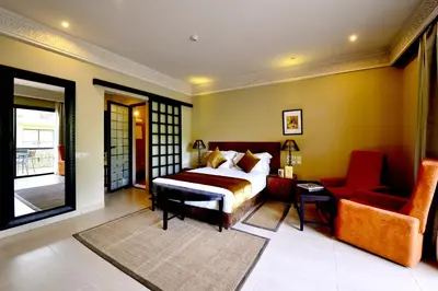 a bedroom with a bed and a couch and a chair at Adam Park Marrakech Hotel & Spa in Marrakech