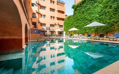 a swimming pool with chairs and umbrellas next to a building at Hotel Oudaya & Spa in Marrakech