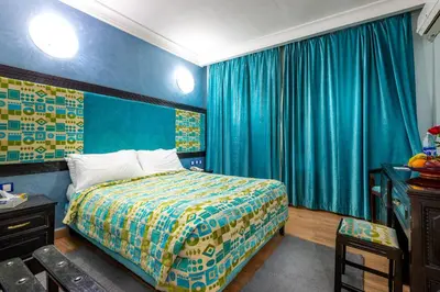 a bedroom with a bed with blue walls and blue curtains at Hotel Oudaya & Spa in Marrakech