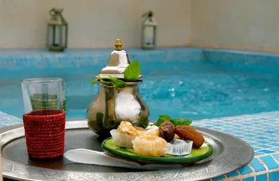 a plate of food on a table next to a pool at Riad Vert in Marrakech
