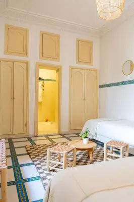 a room with two beds and a table in it at Riad Le Marocain in Marrakech