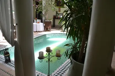 a swimming pool in a house with a table and plants at Riad Alida in Marrakech