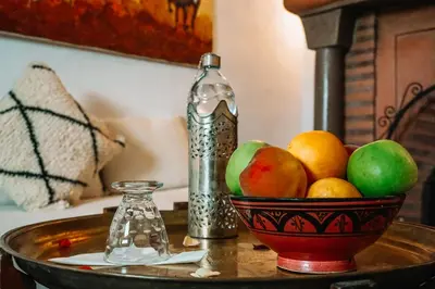 a bowl of fruit on a table with a bottle at Riad Nora in Marrakech